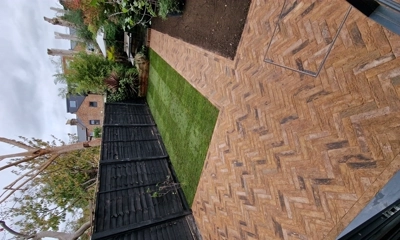 London Mixture clay paver patio encircled by lush turf and planters.