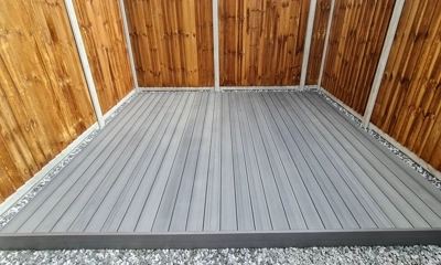 Modern grey composite decking framed by stylish black ice stones.
