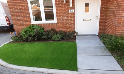 Entrance adorned with vibrant artificial lawn, welcoming and visually pleasing.