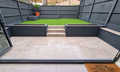 Precise porcelain slabs align with indoor tiles, framed by blue planters.