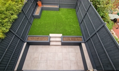 Sleek porcelain tiles encased by deep blue planters and artificial lawn.