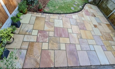 Fossil mint sandstone patio, adorned with curved cobbled edging details în Walthamstow 