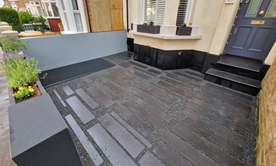Chic front garden with granite planks arranged in captivating, random patterns .Forest Gate gardener