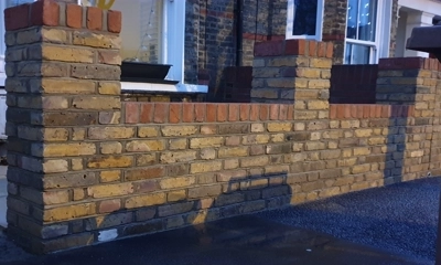 Reclaimed yellow stock brick wall adorned with a striking red top course.