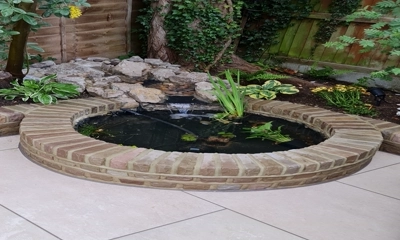 Choose natural pavers for a captivating circular fish pond.