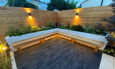 Raised rendered planter behind a wooden bench, complemented by charcoal clay pavers.