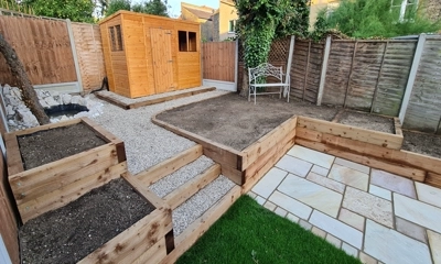 Harmonious landscape project wood sleeper walls, planters, and fossil sandstone patio.