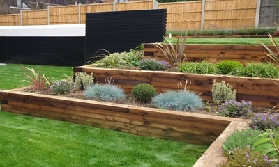 Tiered wood planters harmonize with a stylish black Siberian larch fence.